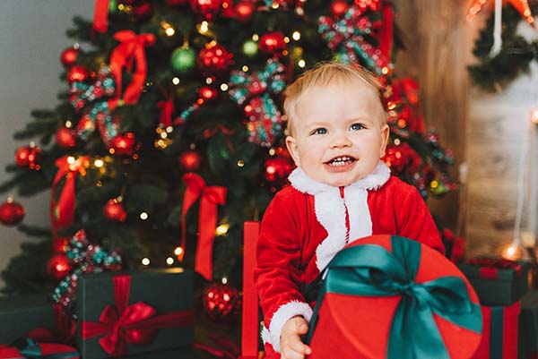 Toddler smiling in front of Christmas Tree
