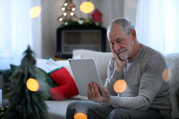 Man holding iPad in decorated room, and looking sad